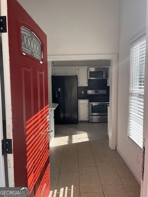 kitchen with tile patterned flooring, stainless steel appliances, and white cabinets