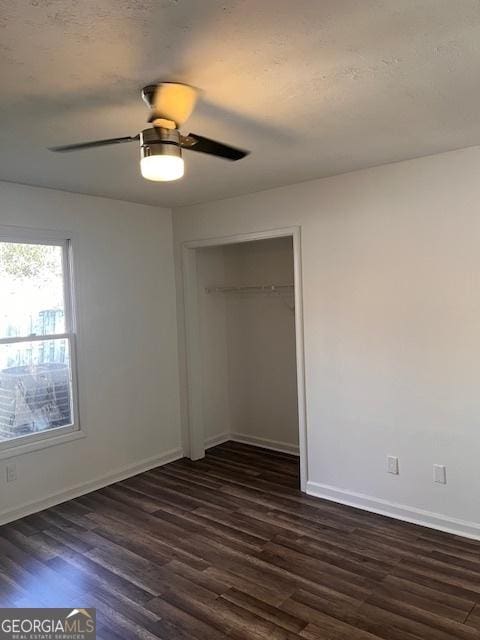 unfurnished bedroom with ceiling fan, dark hardwood / wood-style flooring, a closet, and a textured ceiling