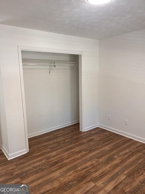 2254 Wellington Cir, Lithonia, GA 30058 - unfurnished bedroom with a closet, dark wood-type flooring, and a textured ceiling