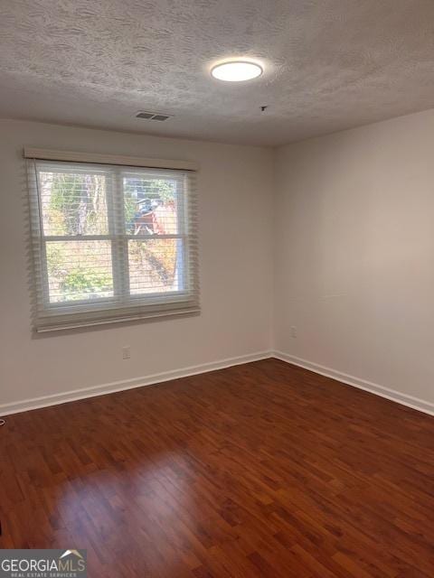 empty room featuring dark wood-type flooring and a textured ceiling