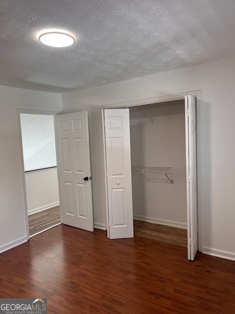 unfurnished bedroom with dark wood-type flooring, a closet, and a textured ceiling