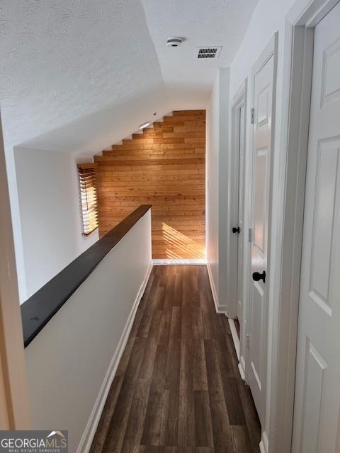 2254 Wellington Cir, Lithonia, GA 30058 - corridor with lofted ceiling, wooden walls, dark wood finished floors, an upstairs landing, and a textured ceiling