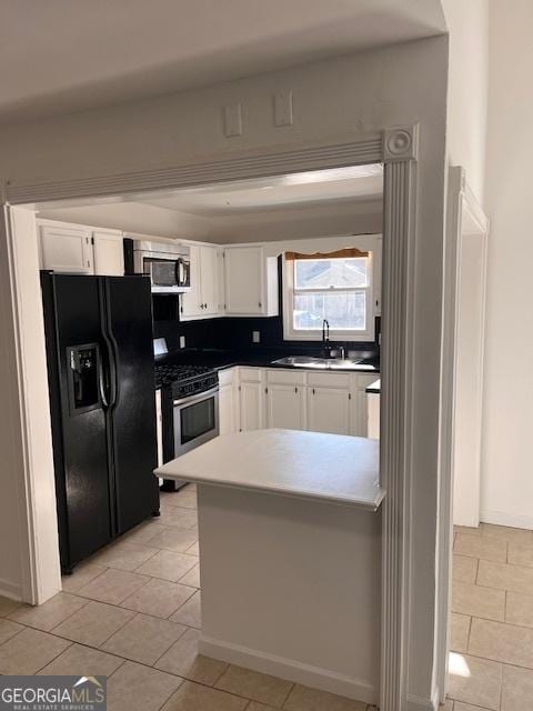 kitchen with stainless steel appliances, white cabinetry, sink, and light tile patterned floors