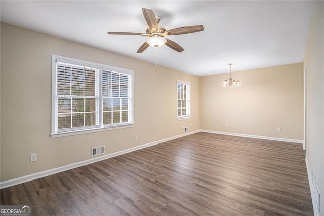 empty room with ceiling fan with notable chandelier and dark wood-type flooring