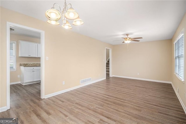 unfurnished room with hardwood / wood-style flooring and ceiling fan with notable chandelier