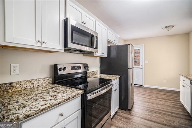 kitchen with light stone countertops, dark hardwood / wood-style flooring, stainless steel appliances, and white cabinetry