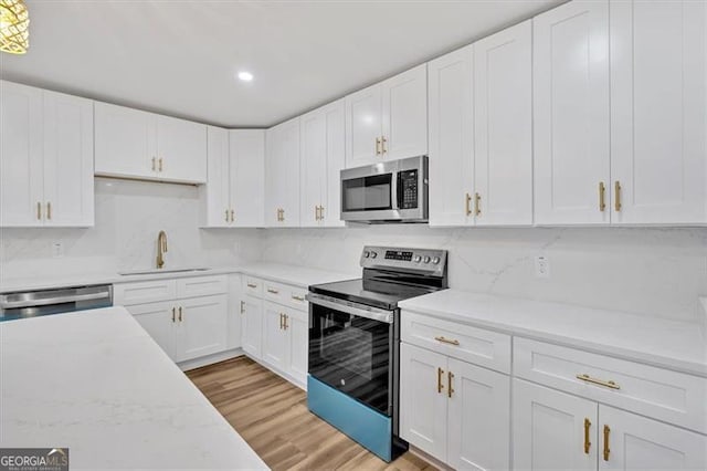 kitchen featuring decorative backsplash, sink, white cabinetry, light wood-type flooring, and stainless steel appliances