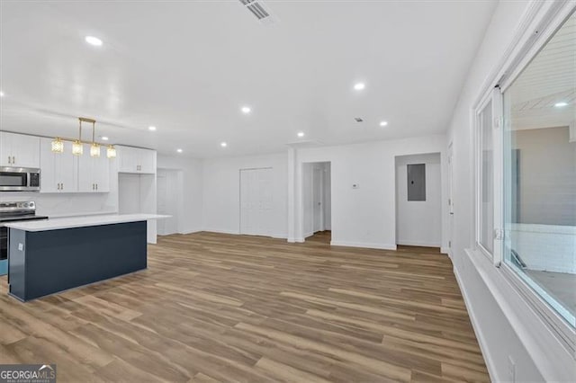 kitchen with hardwood / wood-style flooring, stainless steel appliances, white cabinetry, and a center island