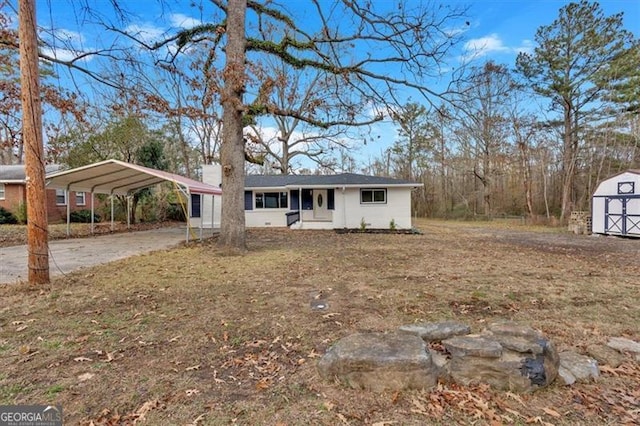 ranch-style home featuring covered porch, a carport, and a storage unit