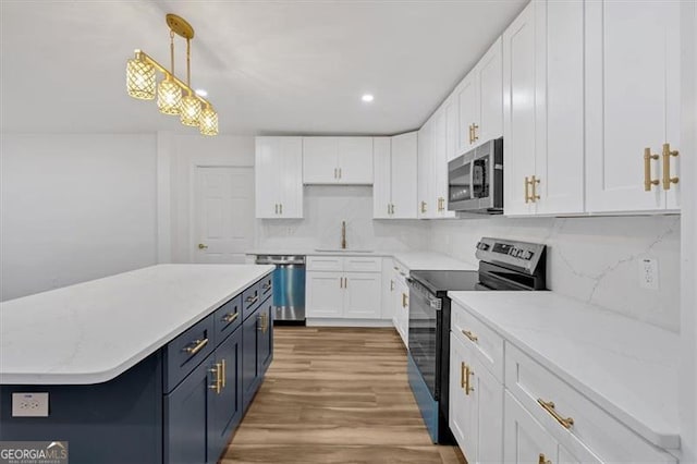 kitchen featuring pendant lighting, appliances with stainless steel finishes, white cabinetry, sink, and blue cabinetry