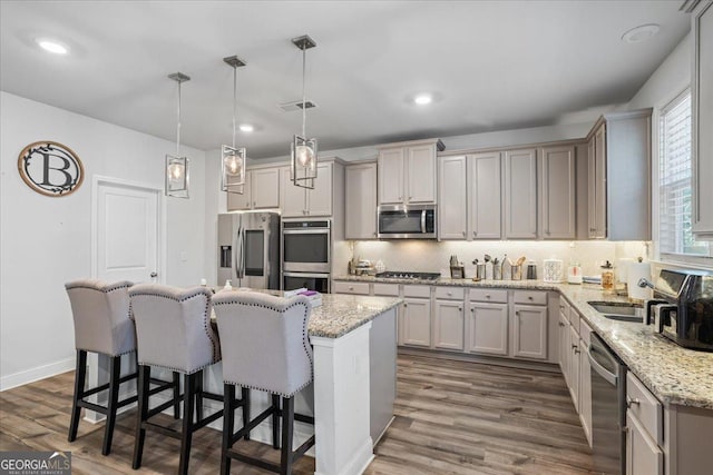 kitchen with dark hardwood / wood-style flooring, a center island, pendant lighting, and appliances with stainless steel finishes