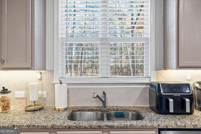 kitchen with light stone counters, sink, and tasteful backsplash