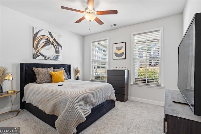 bedroom with ceiling fan, light colored carpet, and multiple windows