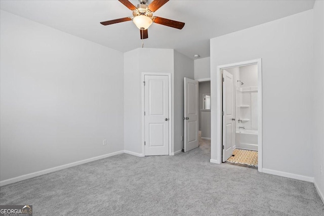 unfurnished bedroom with ensuite bath, ceiling fan, a spacious closet, light carpet, and a closet