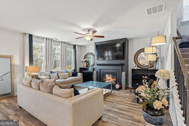 living room featuring ceiling fan, a fireplace, and hardwood / wood-style floors