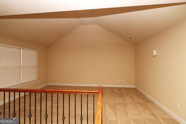 bonus room with light colored carpet and vaulted ceiling