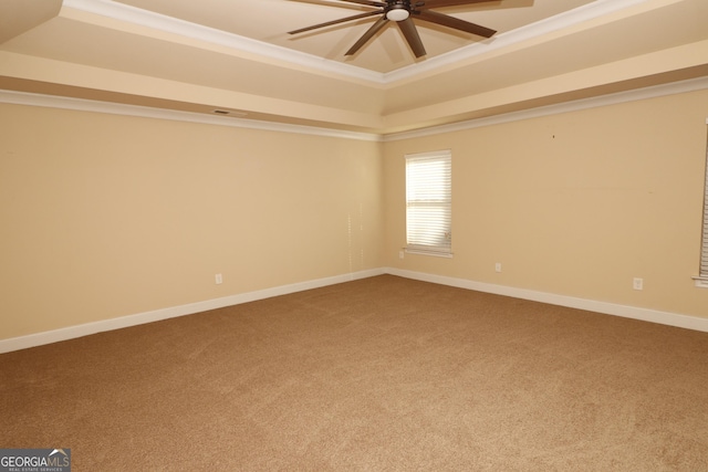 carpeted empty room featuring a raised ceiling, ceiling fan, and ornamental molding