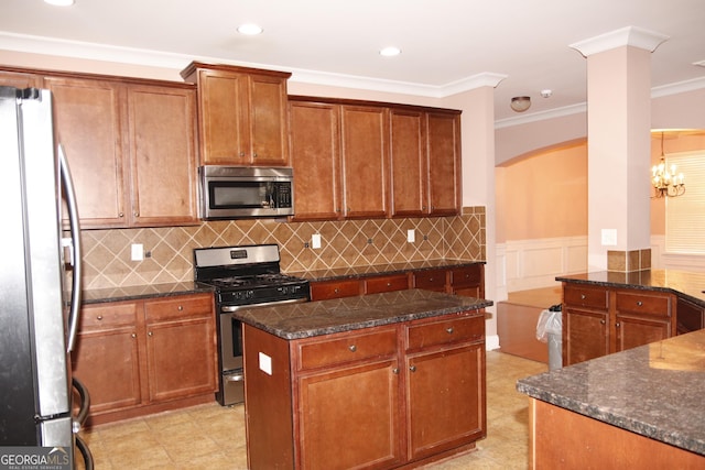 kitchen featuring a center island, an inviting chandelier, dark stone countertops, appliances with stainless steel finishes, and ornamental molding