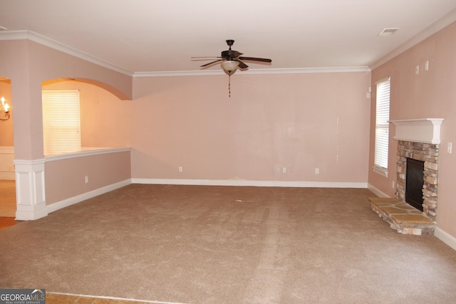 unfurnished living room featuring carpet flooring, a stone fireplace, ceiling fan, and ornamental molding