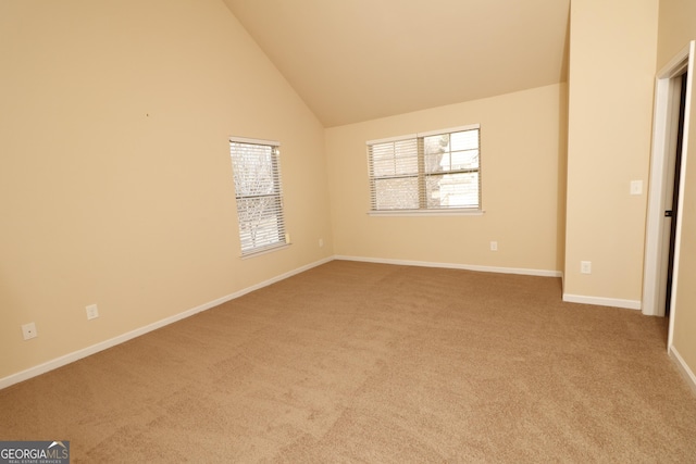 carpeted spare room featuring high vaulted ceiling