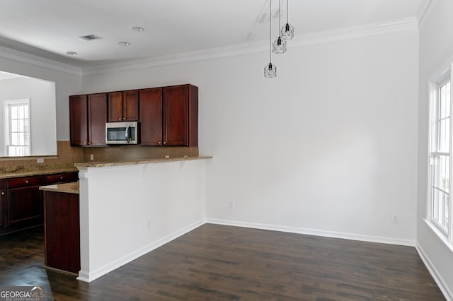 kitchen featuring dark hardwood / wood-style flooring, light stone countertops, plenty of natural light, and hanging light fixtures