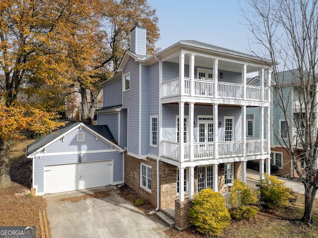 view of front facade featuring a balcony, an outbuilding, french doors, and a garage