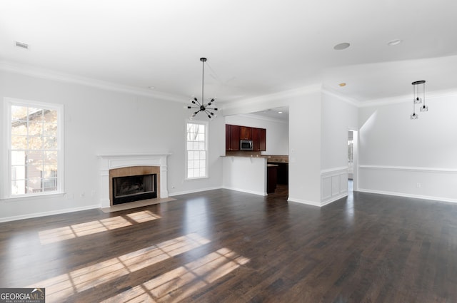 unfurnished living room featuring crown molding, a fireplace, dark wood-type flooring, and an inviting chandelier