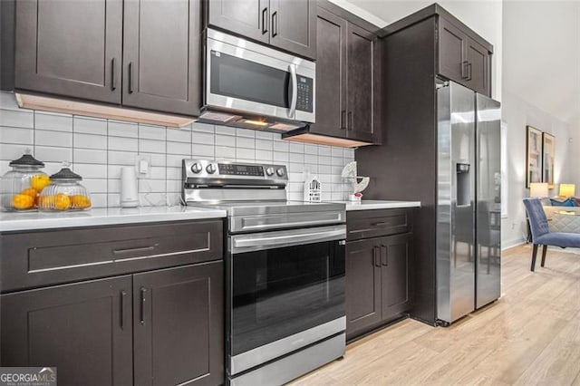 kitchen featuring decorative backsplash, dark brown cabinets, stainless steel appliances, and light wood-type flooring