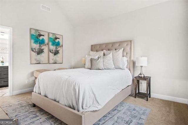 carpeted bedroom with vaulted ceiling and ensuite bath