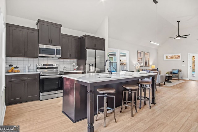 kitchen with an island with sink, sink, a breakfast bar area, light hardwood / wood-style floors, and stainless steel appliances