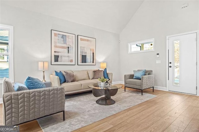 living room featuring high vaulted ceiling and light hardwood / wood-style flooring