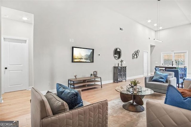 living room with light hardwood / wood-style floors and a high ceiling