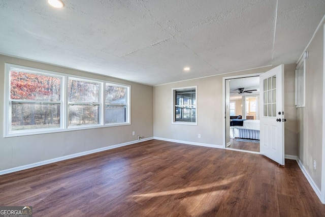 spare room featuring a wealth of natural light, dark hardwood / wood-style floors, and a textured ceiling