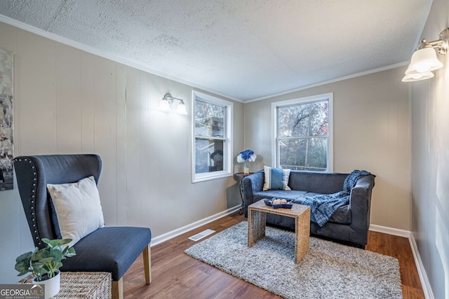 living area with hardwood / wood-style flooring, ornamental molding, and a textured ceiling