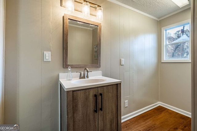 bathroom with crown molding, wood-type flooring, a textured ceiling, and vanity