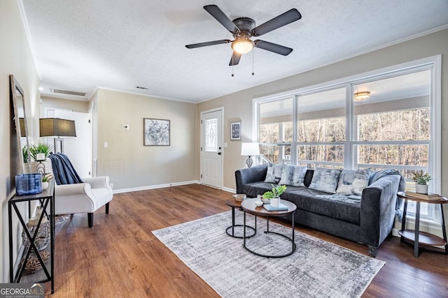 living room with ornamental molding, dark hardwood / wood-style floors, ceiling fan, and a textured ceiling