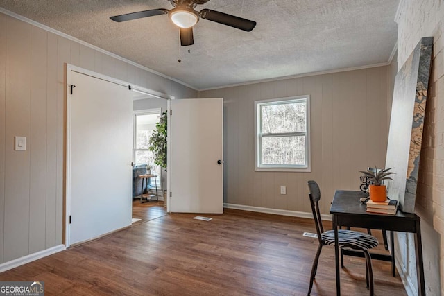 home office featuring wood-type flooring, ornamental molding, ceiling fan, and a textured ceiling