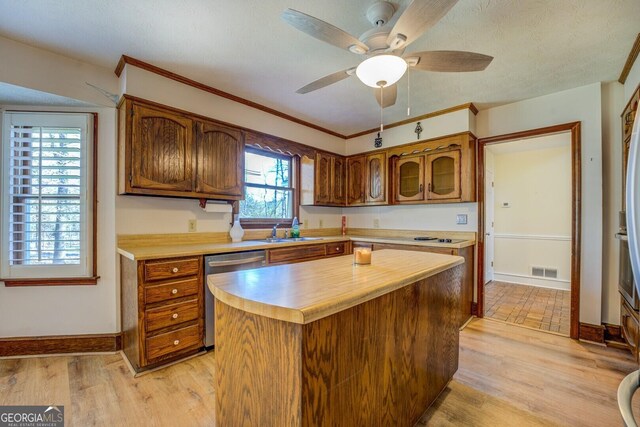 kitchen featuring stainless steel dishwasher, sink, a center island, light hardwood / wood-style floors, and plenty of natural light