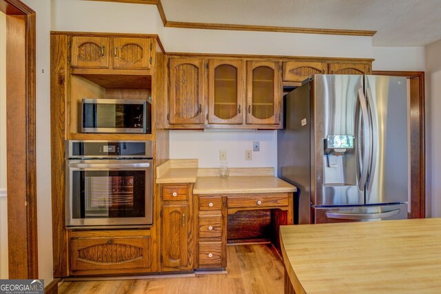 kitchen featuring appliances with stainless steel finishes, light wood-type flooring, and crown molding