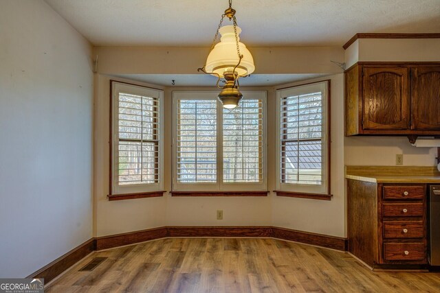 unfurnished dining area featuring a textured ceiling and light wood-type flooring