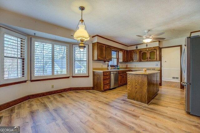 kitchen with light wood-type flooring, stainless steel appliances, ceiling fan, pendant lighting, and a center island