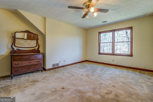 unfurnished bedroom featuring a textured ceiling, ceiling fan, and light carpet