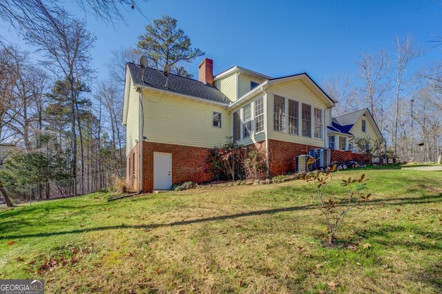 view of property exterior featuring a sunroom and a yard