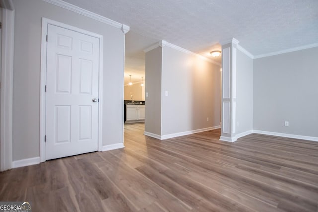 spare room featuring crown molding, hardwood / wood-style floors, and a textured ceiling