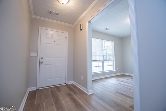 foyer entrance featuring crown molding, wood-type flooring, and a textured ceiling