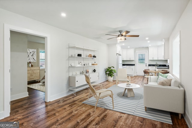 living room featuring ceiling fan, sink, and dark wood-type flooring