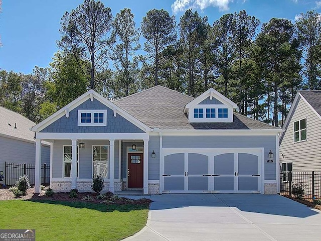 craftsman house featuring covered porch, a garage, and a front lawn