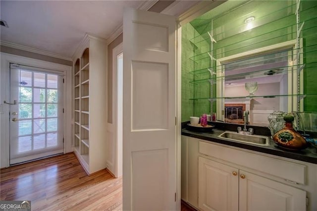 bar with crown molding, white cabinetry, sink, and light hardwood / wood-style floors