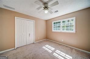 unfurnished bedroom with ceiling fan, a closet, and carpet