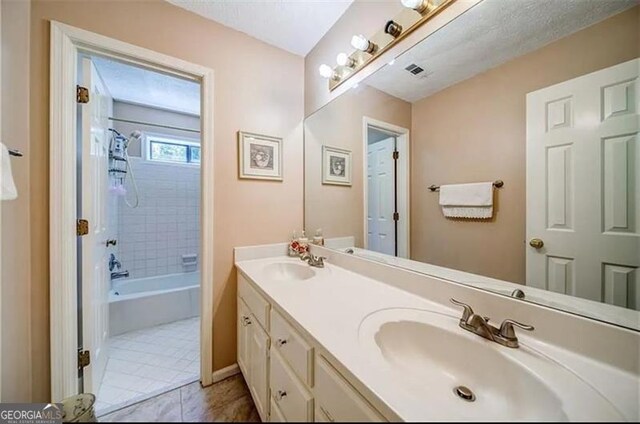 bathroom with tile patterned flooring, vanity, and tiled shower / bath combo